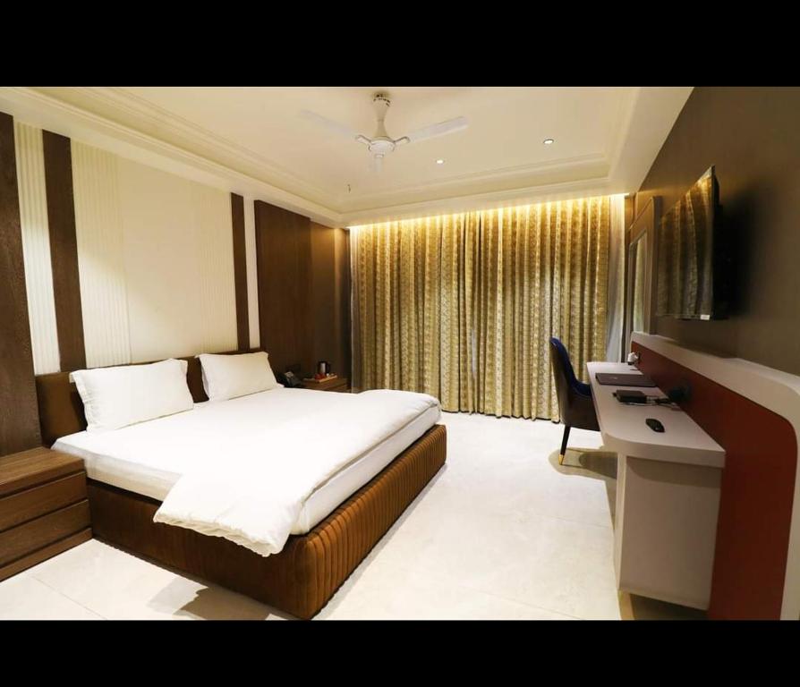 a bedroom with a bed and a desk and a window at SWARN INN AND SUITES in Muzaffarnagar