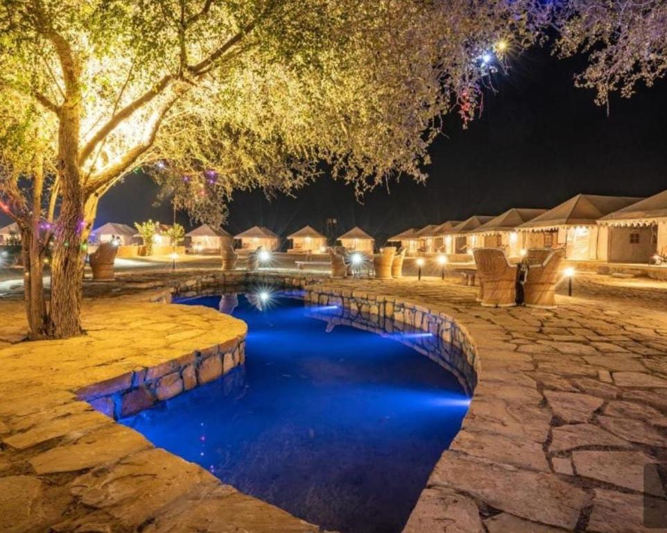 a resort pool with blue water at night at Night Stay Camp in Jaisalmer