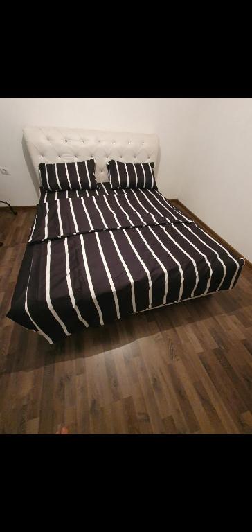 un letto bianco e nero su un pavimento in legno di BIANCA LuX a Kraljevo