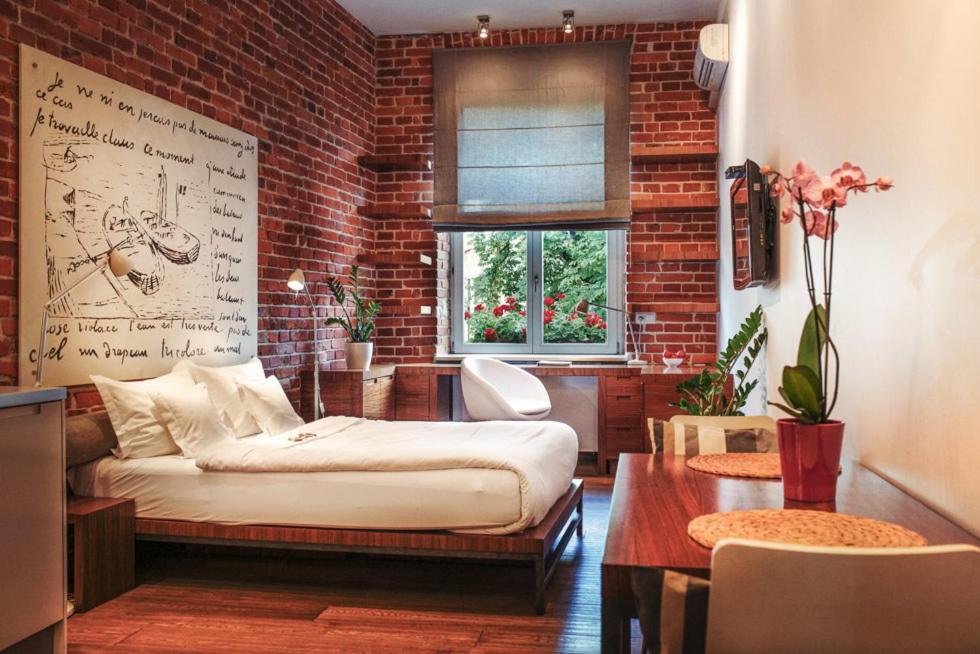 a room with a bed and a brick wall at Apartamenty Straszewskiego in Krakow