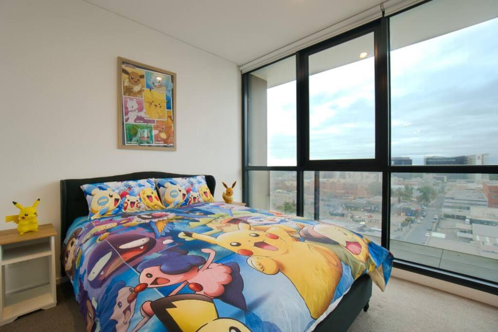 Schlafzimmer mit einem Bett und einem großen Fenster in der Unterkunft Pokémon Inspired Apt -Pool-Gym-Sauna-Steam Room in Adelaide