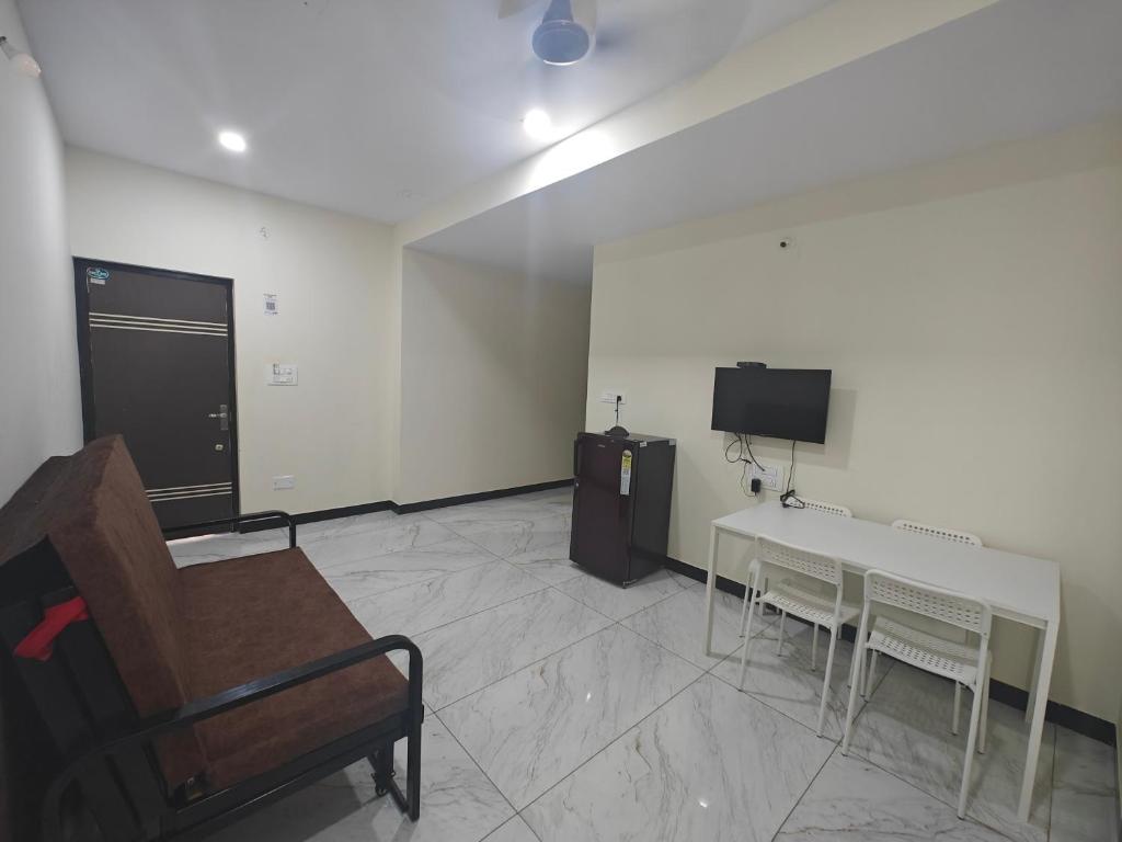 a room with a table and a tv and a couch at Comfort Cove Apartments in Mysore