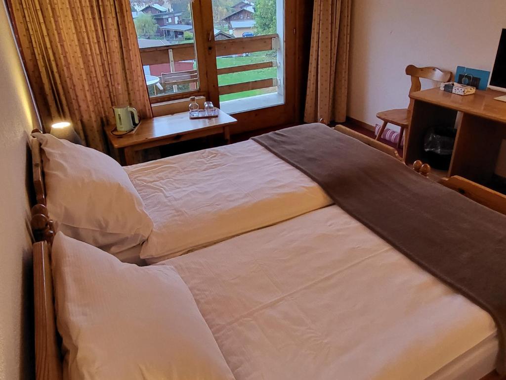 two beds in a hotel room with a window at La Tour d'Aï in Leysin