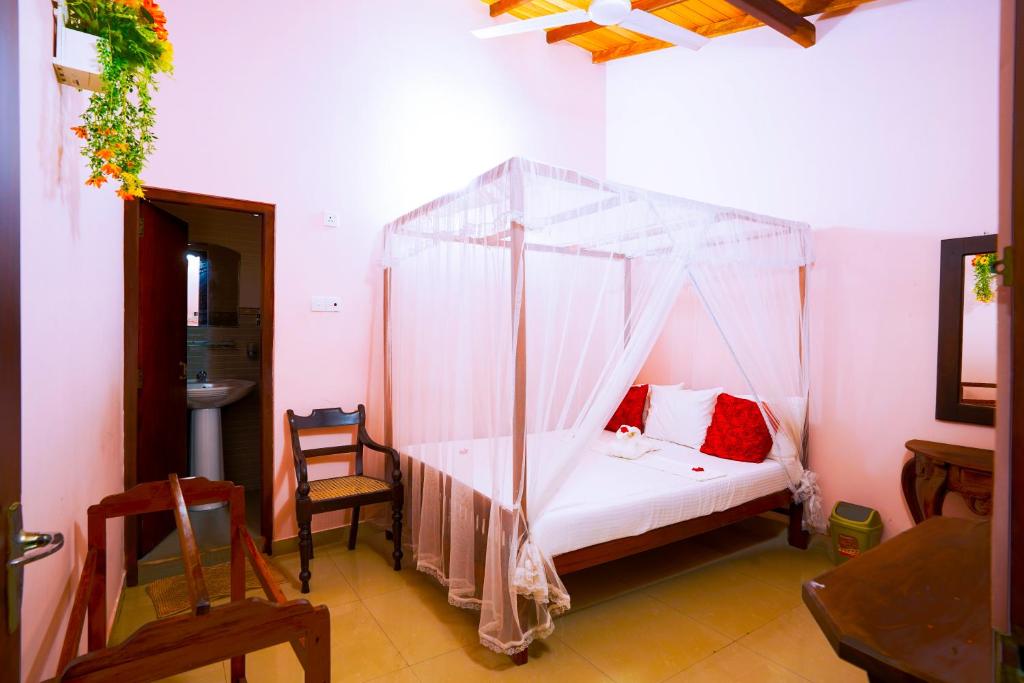 a bedroom with a bed with a mosquito net at The Frangipani motel in Galle