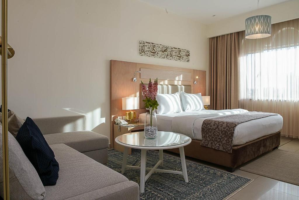 um quarto de hotel com uma cama e um sofá em Toledo Amman Hotel em Amã