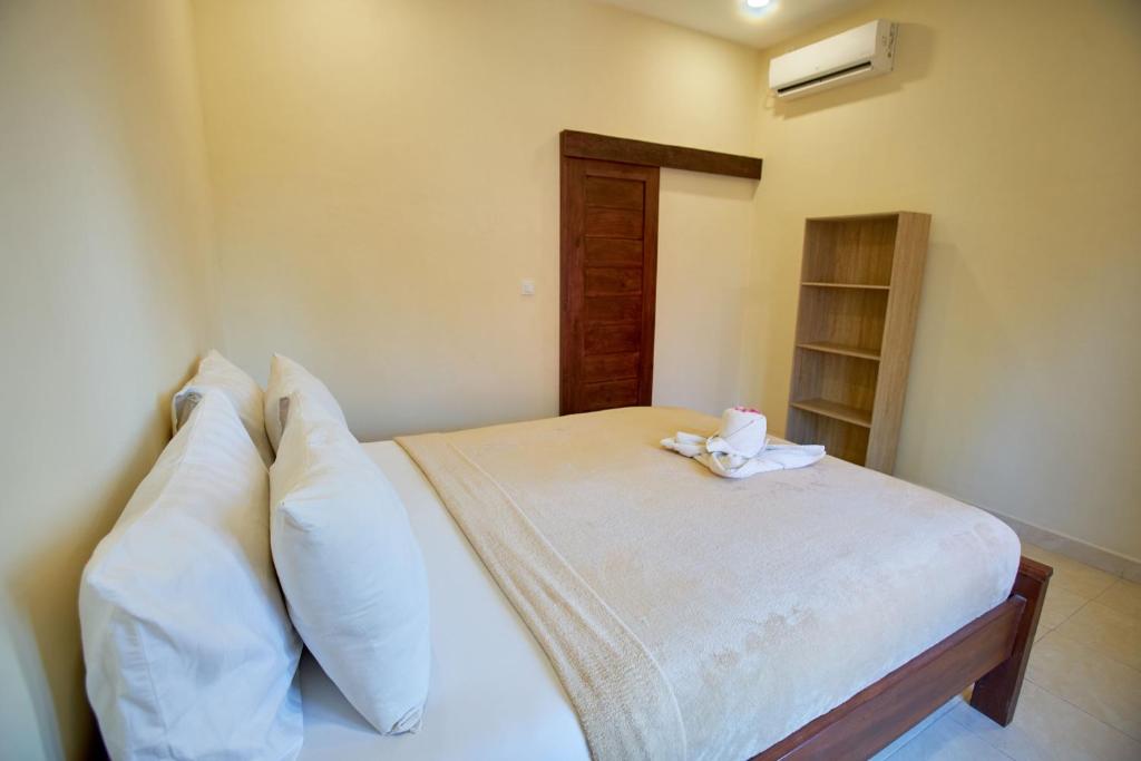 1 dormitorio con 1 cama con sábanas y almohadas blancas en Risna Homestay, en Nusa Lembongan