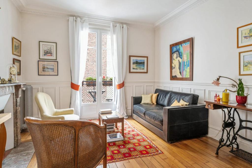 - un salon avec un canapé et des fauteuils en cuir noir dans l'établissement Appartement Mélèze - Welkeys, à Paris