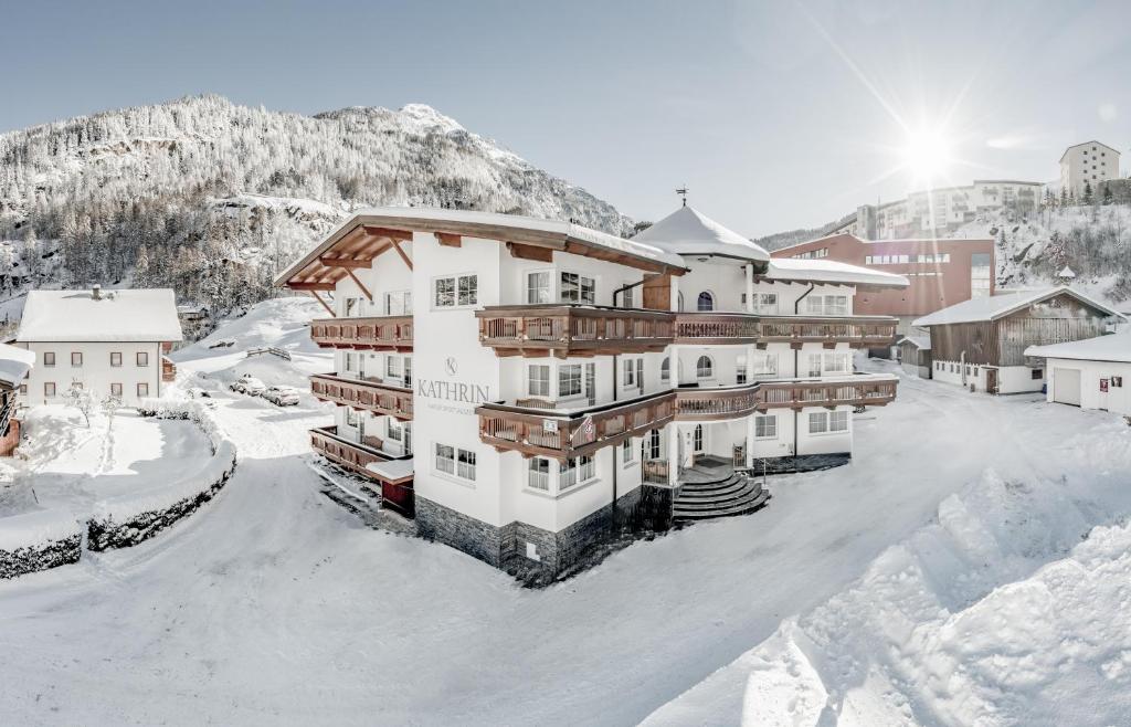 un hotel en la nieve con una montaña en el fondo en Appartementhaus Kathrin, en Sölden
