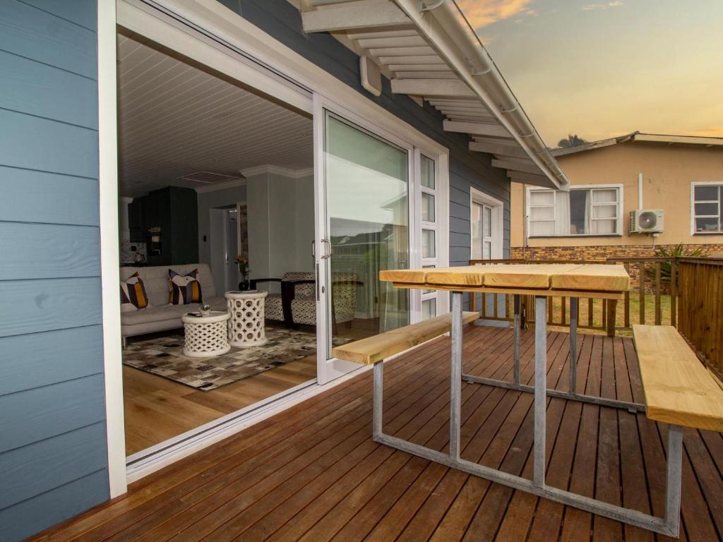 a deck with a table and bench on a house at 1 Harbour Way in Gansbaai