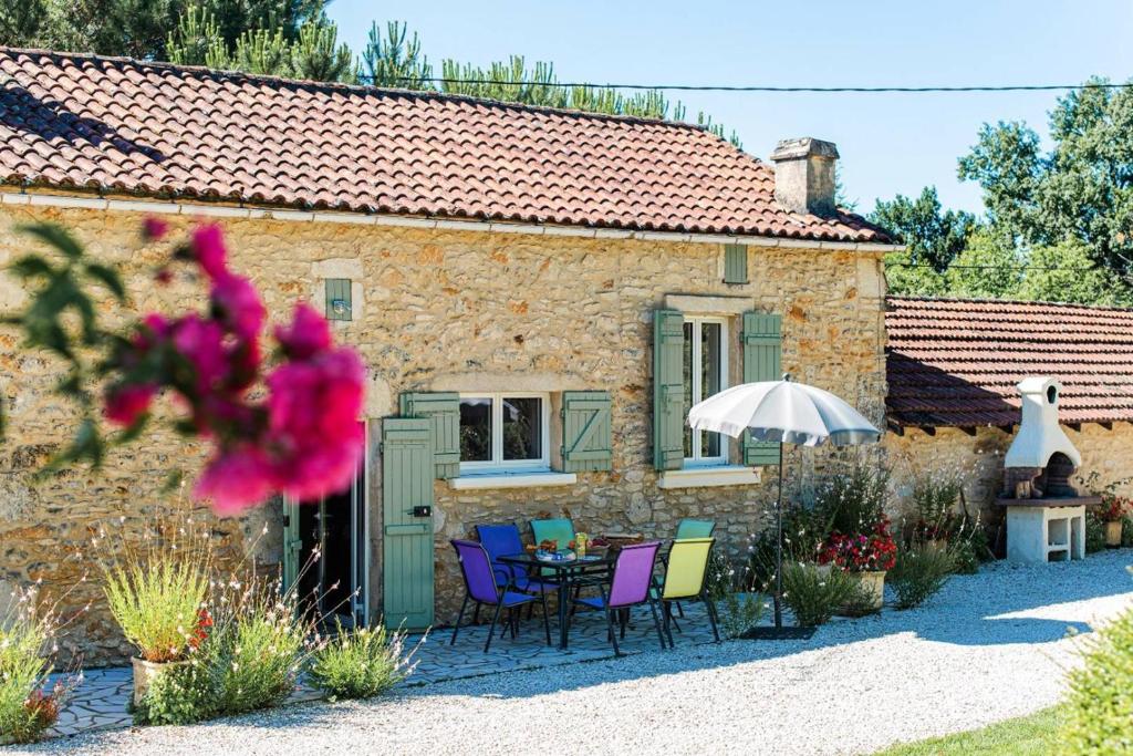 un cottage in pietra con tavolo, sedie e ombrellone di Le Cayroux - Clévacances 3 clés a Blanquefort-sur-Briolance