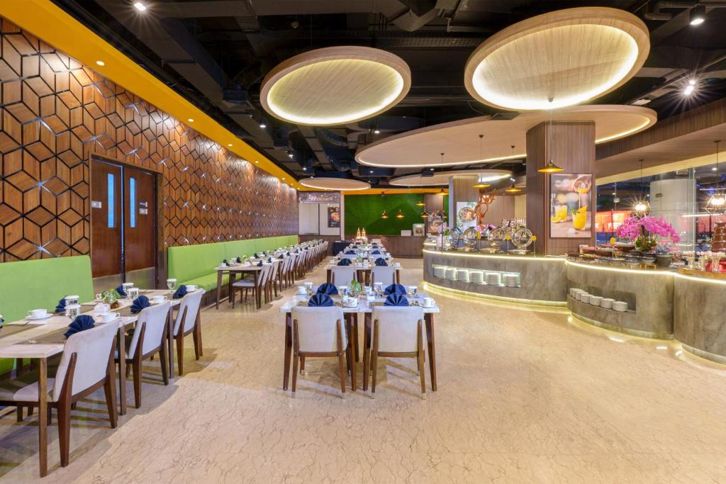 a dining room with tables and chairs and lights at Golden Tulip Springhill Lampung in Bandar Lampung