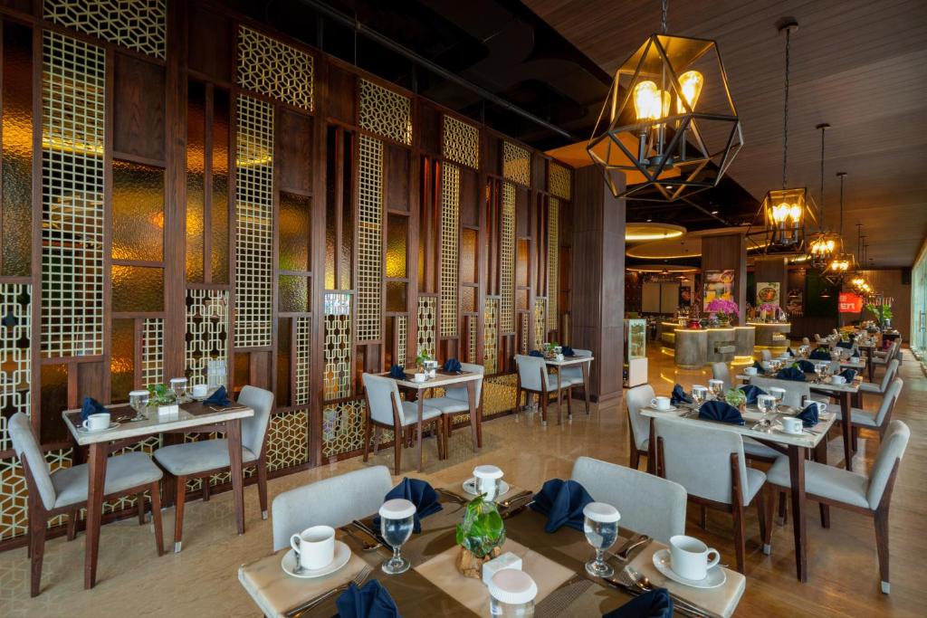 a restaurant with tables and chairs in a room at Golden Tulip Springhill Lampung in Bandar Lampung