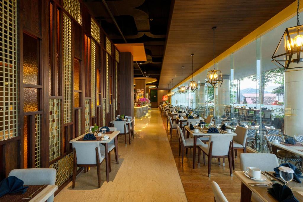 a dining room with tables and chairs in a restaurant at Golden Tulip Springhill Lampung in Bandar Lampung
