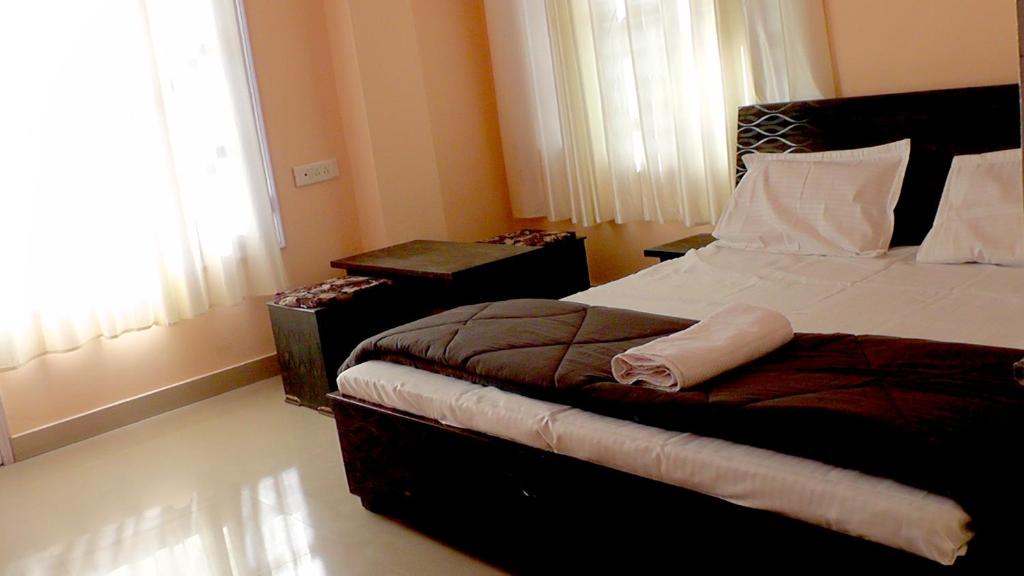 a bedroom with a bed and a table and a window at Lakshay Regency in Shimla