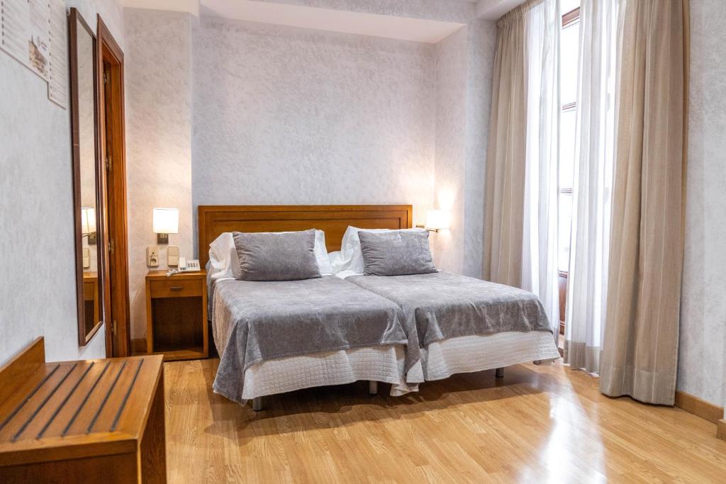um quarto com uma cama, uma mesa e uma janela em Hotel Granada Centro em Granada