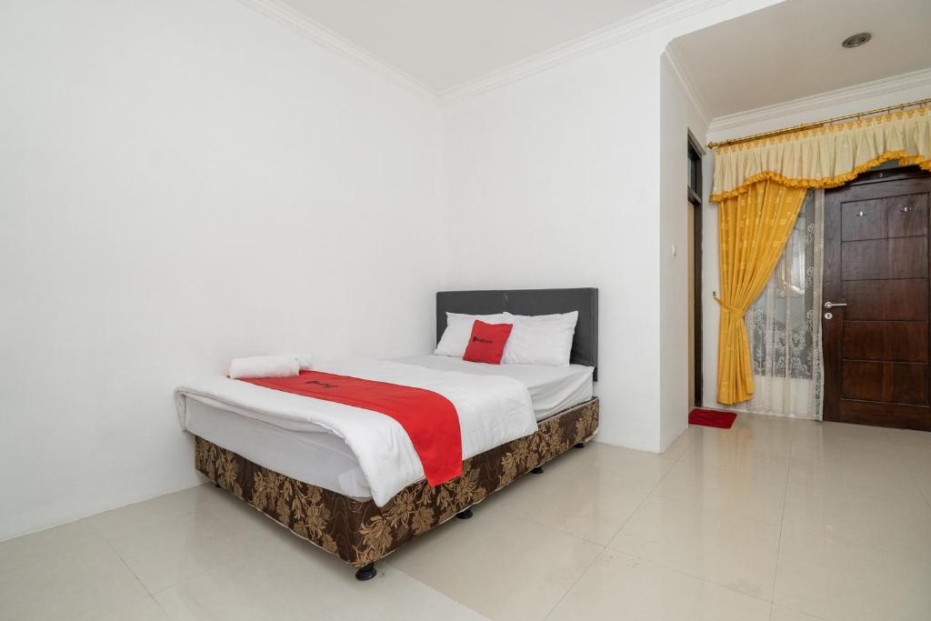 een slaapkamer met een bed met een rode deken bij Grha Rahadi 2 Wiyung RedPartner in Surabaya