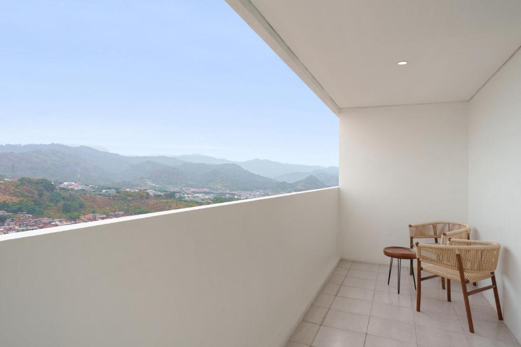 a room with two chairs and a view of the mountains at Golden Tulip Springhill Lampung in Bandar Lampung
