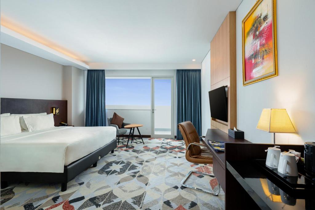 a hotel room with a bed and a television at Golden Tulip Springhill Lampung in Bandar Lampung