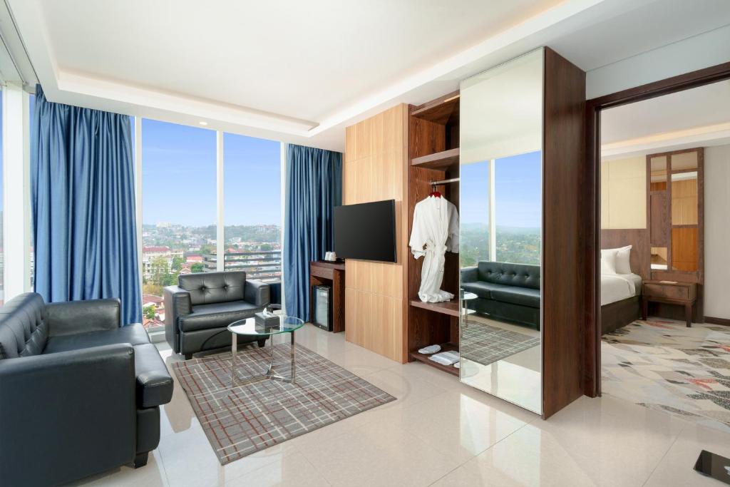 a hotel room with a suite with a bed and a television at Golden Tulip Springhill Lampung in Bandar Lampung