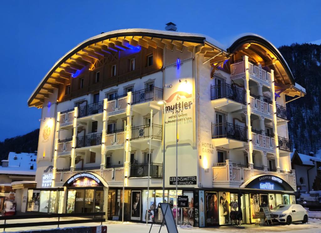 un grande edificio bianco con un arco davanti di Hotel Garni Muttler Alpinresort & Spa a Samnaun