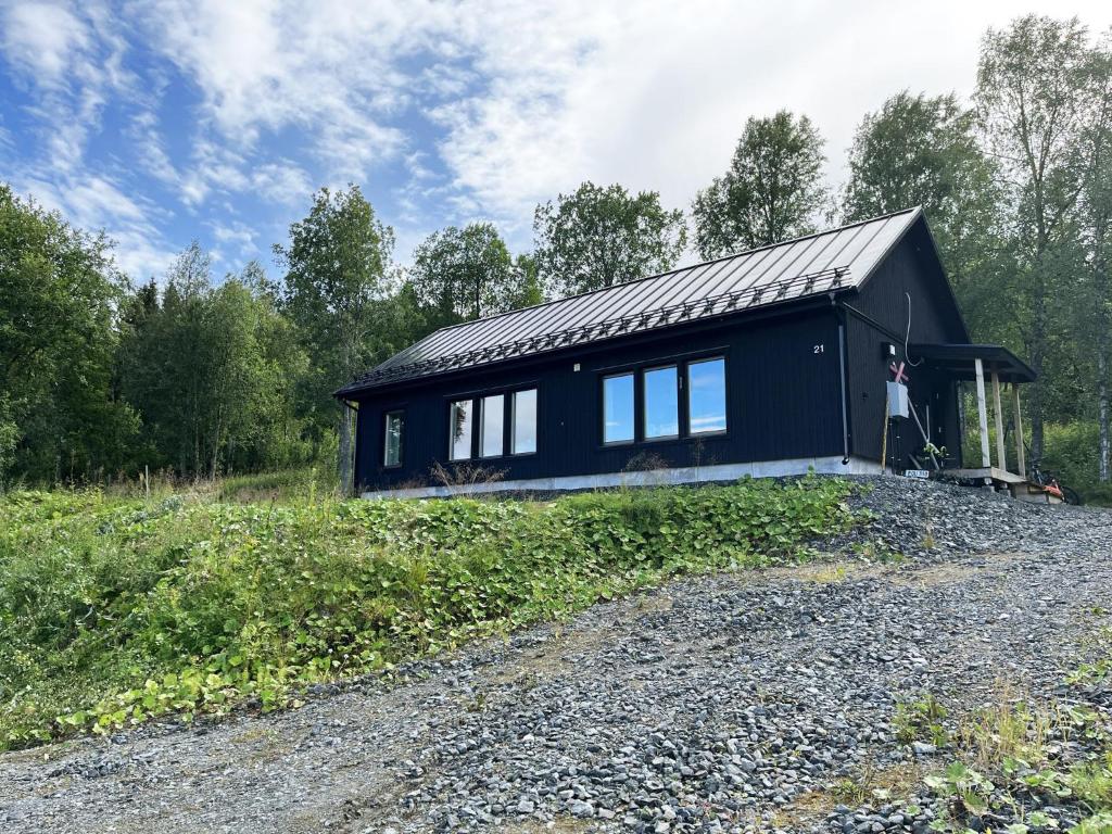 uma casa preta ao lado de uma estrada de cascalho em Mountain cabin with a magically beautiful view in Husa near Are em Järpen