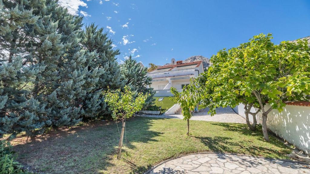 a garden in front of a house with trees at Große Terrasse mit Meerblick, Strand 200 Meter in Baška