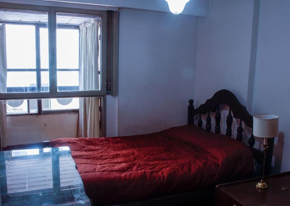 - une chambre avec un lit rouge et une fenêtre dans l'établissement 2 Departamento pleno Centro todo equipado, à Córdoba