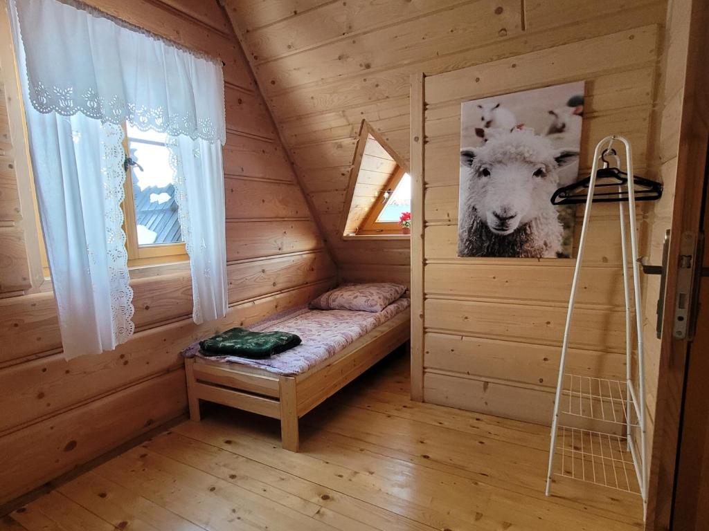 um quarto com uma cama num camarote com uma fotografia de uma ovelha em Domek u Beaty em Dzianisz