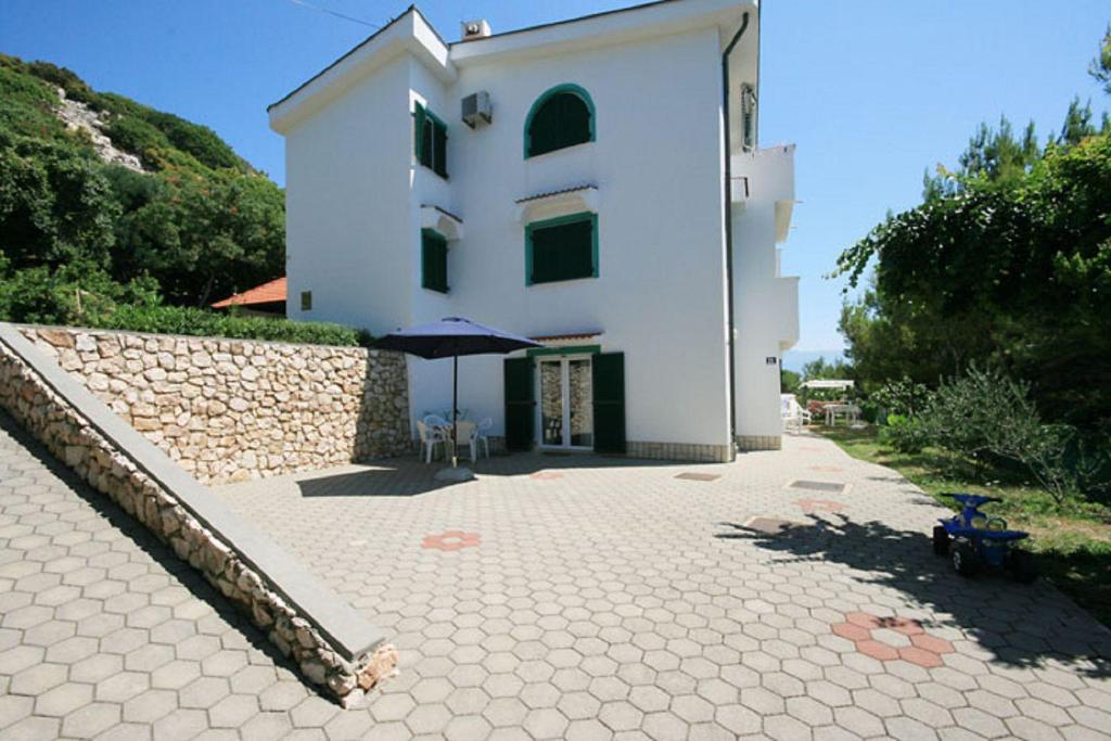 a white building with an umbrella in front of it at 100 Meter zur kristallklaren Adria in Baška