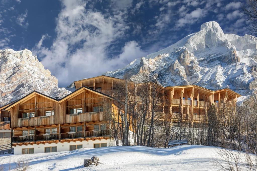 a building in the snow with mountains in the background at Hotel Rezia in La Villa