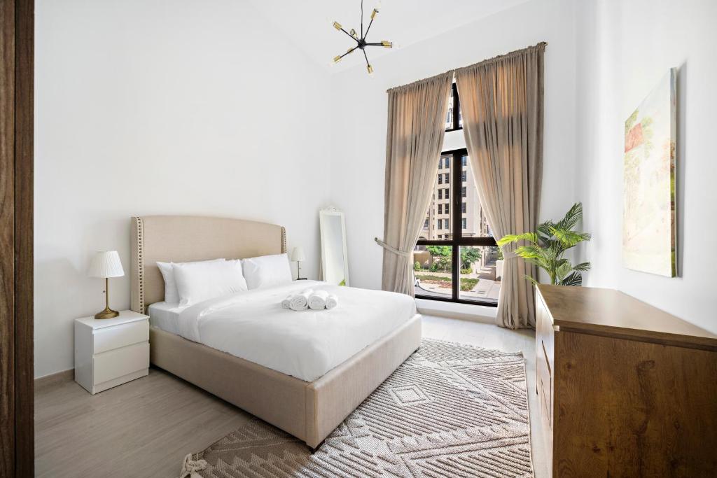 a white bedroom with a bed and a window at Stylish 1BR Apt Umm Suqeim 3 in Dubai