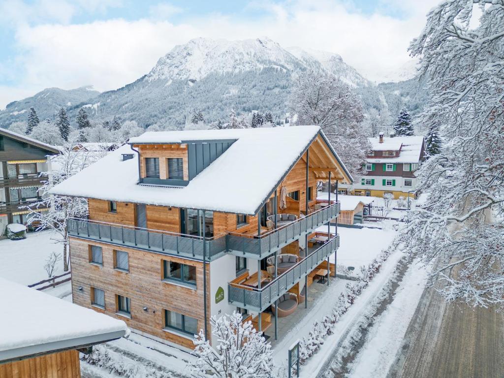 a house covered in snow with mountains in the background at Dorf Suites in Oberstdorf
