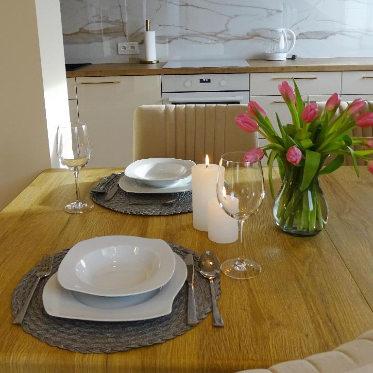 a table with plates and glasses and a vase of flowers at Apartamenty u ROXI in Jelenia Góra