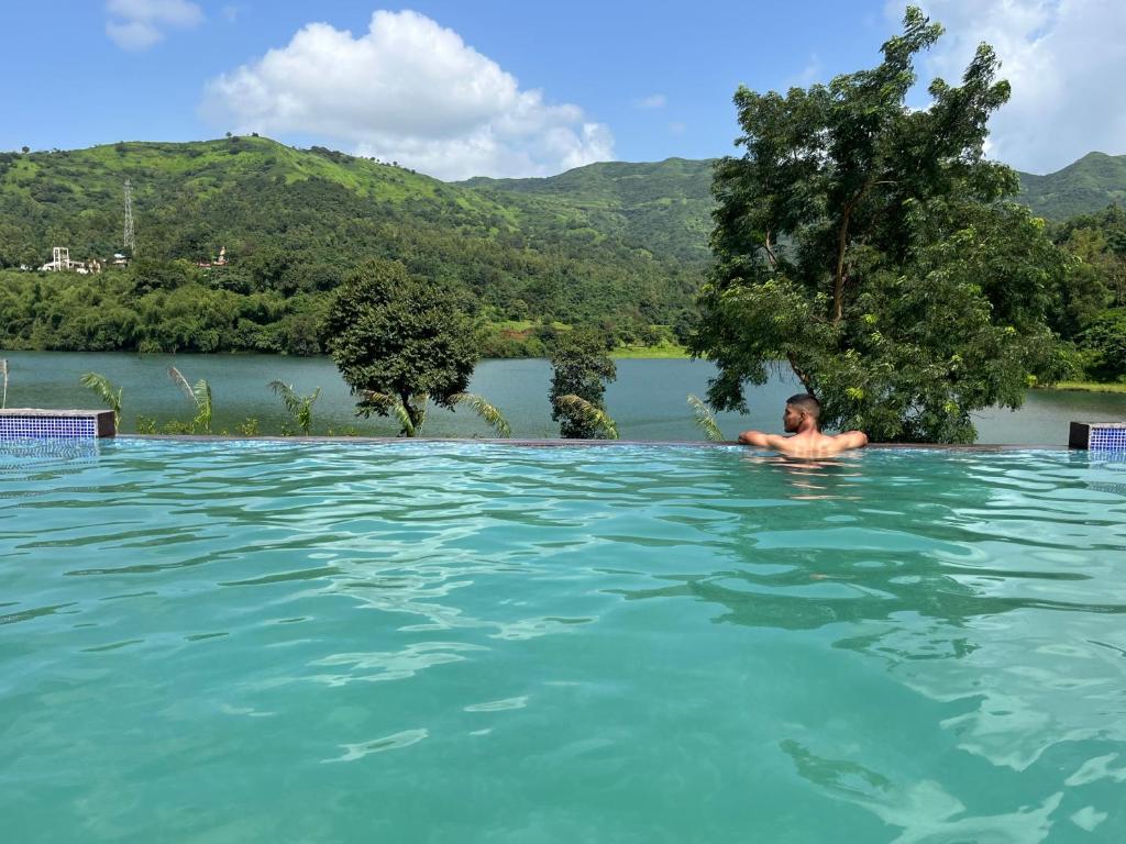 Un uomo in una piscina in un fiume di VRISA Mountain Retreat a Pune