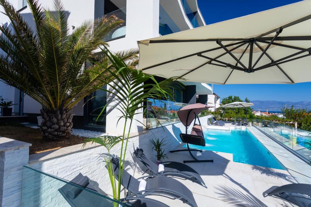 a pool with an umbrella next to a building at Villa Valis in Baška