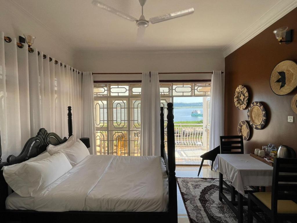 a bedroom with a bed and a table and a window at The Jewel and the Lake in Jinja