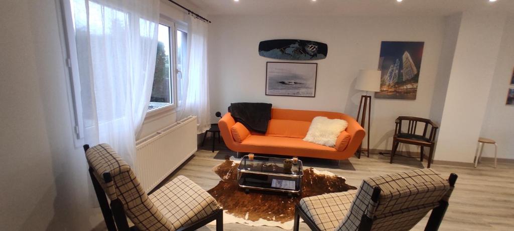 an orange couch and two chairs in a living room at Freddy's house in Wimille
