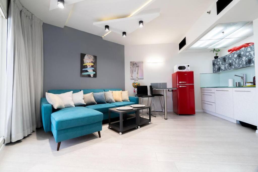uma sala de estar com um sofá azul e um frigorífico vermelho em Sweet Love - דירה מהממת על הים עם נוף em Bat Yam