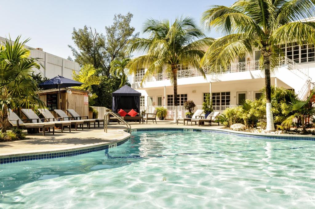 una piscina con palmeras y un edificio en Tradewinds Apartment Hotel Miami Beach, en Miami Beach
