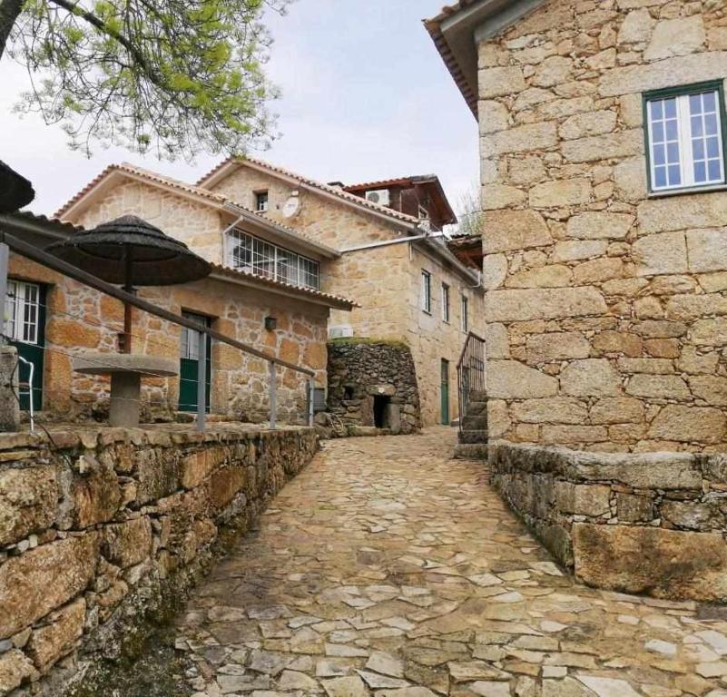 Une allée dans un ancien bâtiment en pierre avec un parasol dans l'établissement Quinta Do Moinho Turismo de Natureza, à Aldeia Viçosa