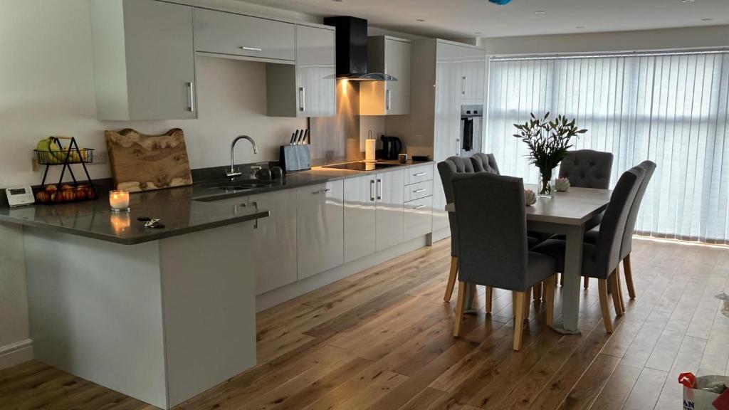 a kitchen with a table and chairs and a kitchen with white cabinets at Honeysuckle Cottage -PART OF ALTON COTTAGES in Alton