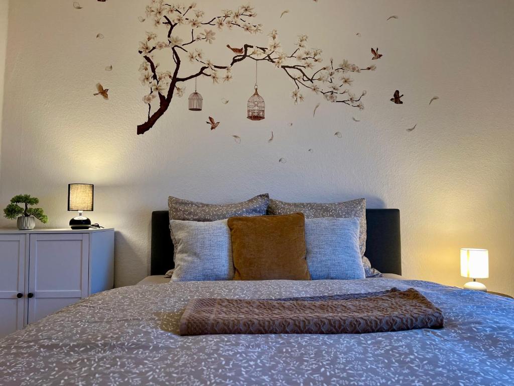 a bedroom with a bed with a tree on the wall at Dejlig 2 værelses lejlighed in Randers