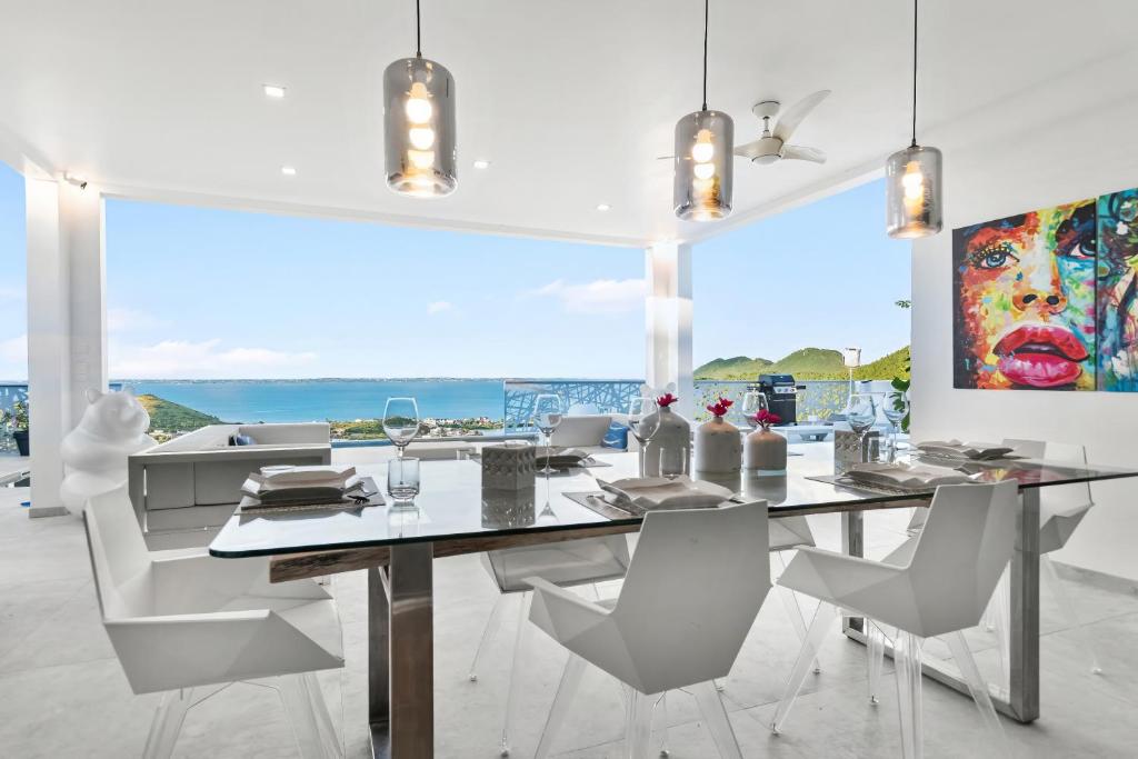 a dining room with a table and chairs and a large window at Grand Case - Villa chic 6p 3ch 3sdb Vue panoramique in Saint Martin