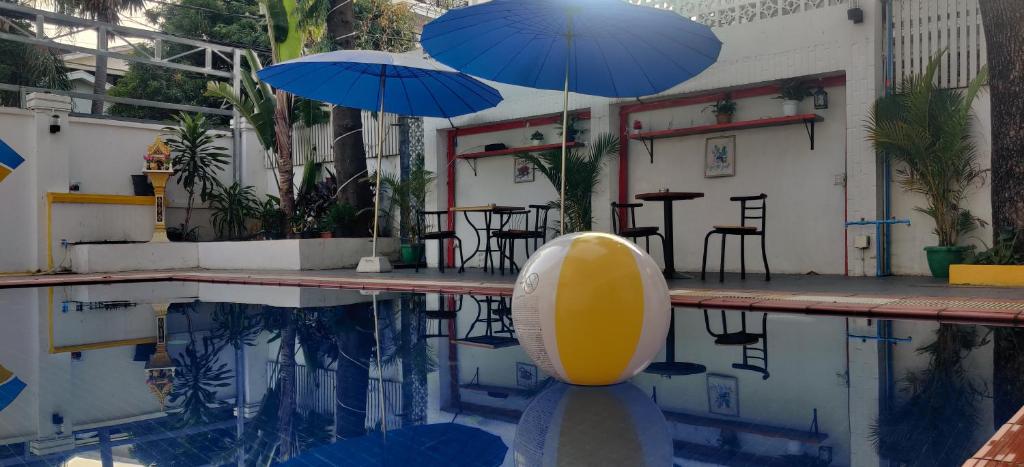 een zwembad met 2 parasols en een tafel en stoelen bij Villa Samnang BOUTIQUE HOTEL in Phnom Penh