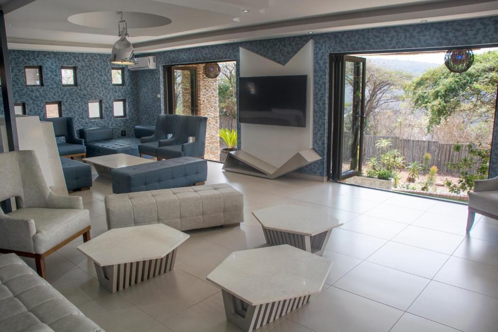 a living room with couches and tables and a tv at Impecto Guest House in Jozini