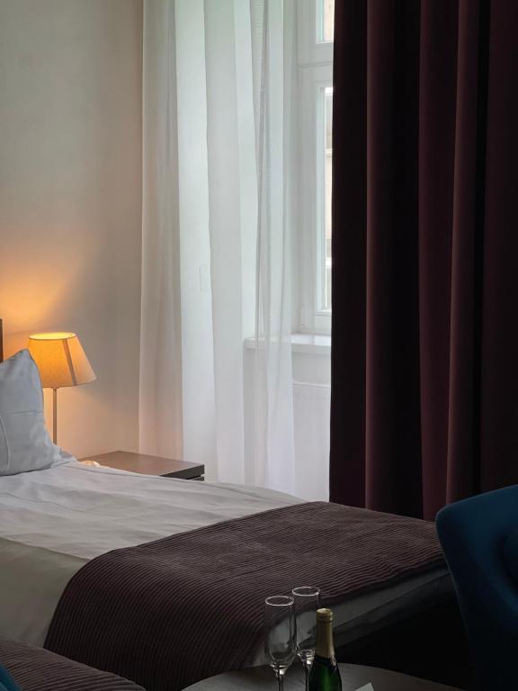 a bedroom with a bed with two glasses and a window at Hotel Residence Spalena in Prague