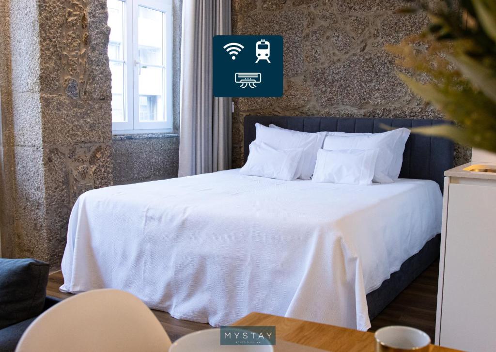 um quarto com uma cama com lençóis brancos e almofadas em MyStay - D Maria Apartments em Vila Nova de Famalicão