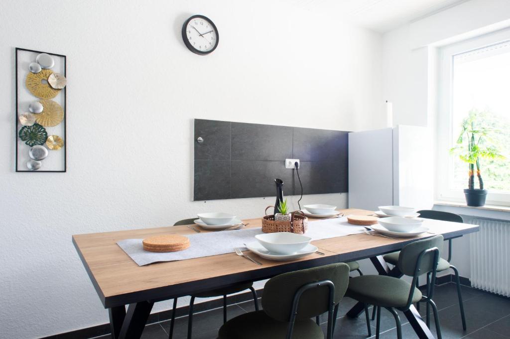 une table à manger avec des chaises et une horloge murale dans l'établissement Moderne Wohnung im Zentrum, à Gronau