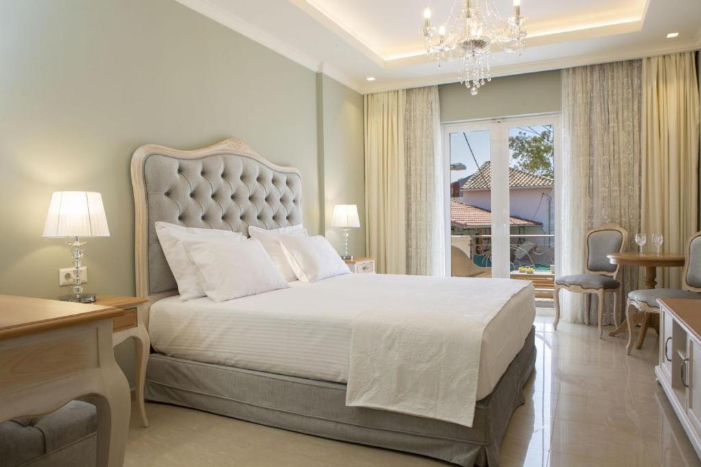 a bedroom with a large white bed with a chandelier at VK Luxury Suites - Private Parking - Adults Only in Nydri