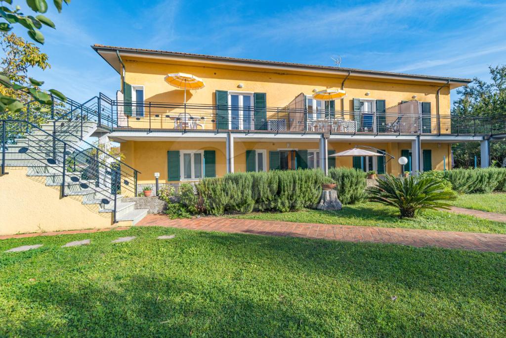 ein großes gelbes Haus mit einem Balkon und einer Treppe in der Unterkunft Residence gli Olmi - Goelba in Marina di Campo